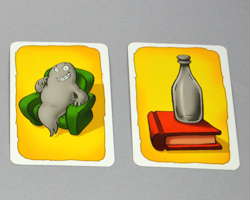 Spielkarten vom Spiel Geistesblitz, zu sehen sind ein grüner Sessel mit einem grauen Geist und eine graue Flasche, die auf einem roten Buch steht.